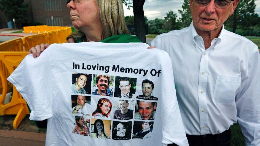 Lonnie and Sandy Phillips, whose daughter Jessica Ghawi was killed in the 2012 Aurora movie theatre massacre, talk with members of the media and display a T-shirt memorializing the twelve people killed in the attack, outside the Arapahoe County District Court following the day of closing arguments in the trial of theater shootings defendant James Holmes, in Centennial, Colo., Tuesday July 14, 2015. (The Associated Press)