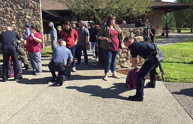 Authorities search bags as students evacuate Umpqua Community College. 