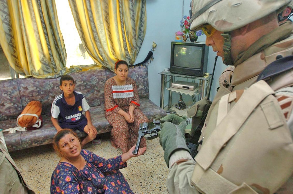 Capt. Dustin Baadte, C Co., 1-64 Armor, commander, asks a woman about a .38 caliber pistol found in her home during a raid in New Baghdad, Iraq, June 6. Civilians need a permit to posess handguns in the Baghdad area.