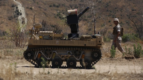 Pfc. Jasper Jauregui, an infantryman with Kilo Company, 3rd Battalion, 5th Regiment, patrols next to the robotic vehicle modular system aboard Camp Pendleton, Calif., June 23, 2016. The system is still in development and will be tested during exercise Rim of the Pacific. The Marine Corps Warfighting Laboratory is conducting a Marine Air-Ground Task Force Integrated Experiment to explore new gear and access its capabilities for potential future use. (U.S. Marine Corps photo by Lance Cpl. Frank Cordoba/Released)