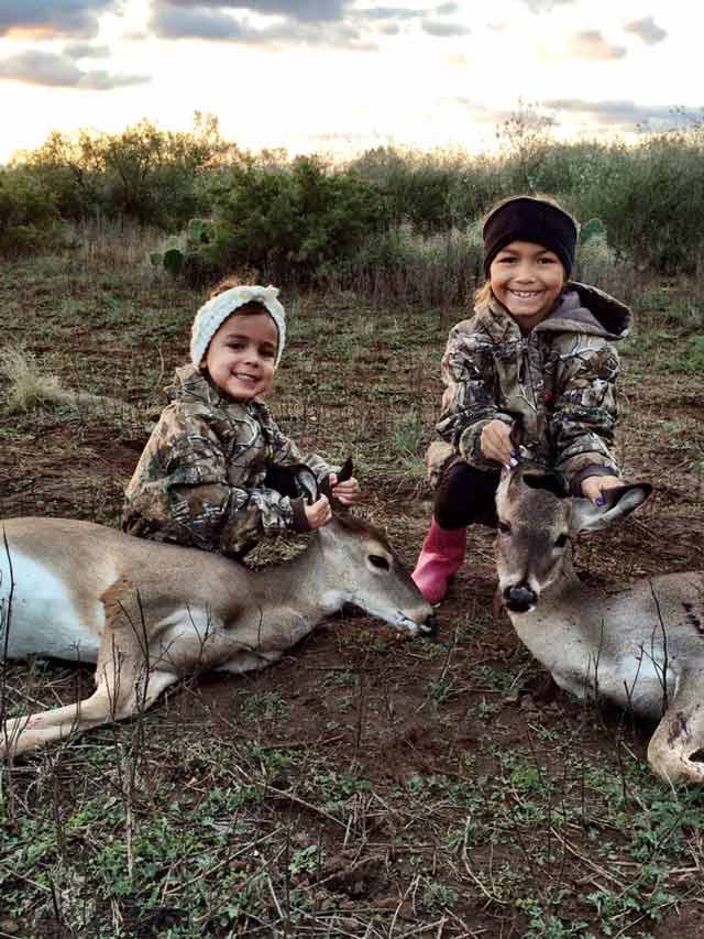 children pose next to hunted deer