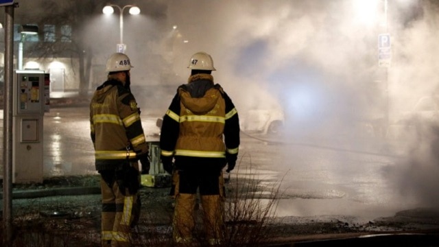 Firefighters attend to cars smoking after being set on fire in a Stockholm suburb (Photo: Reuters)
