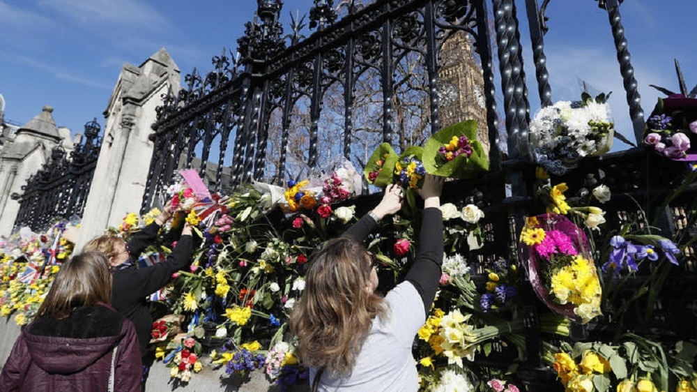 People pay tribute to the victims of the Westminster attack by placing flowers outside Parliament (Photo: AP)
