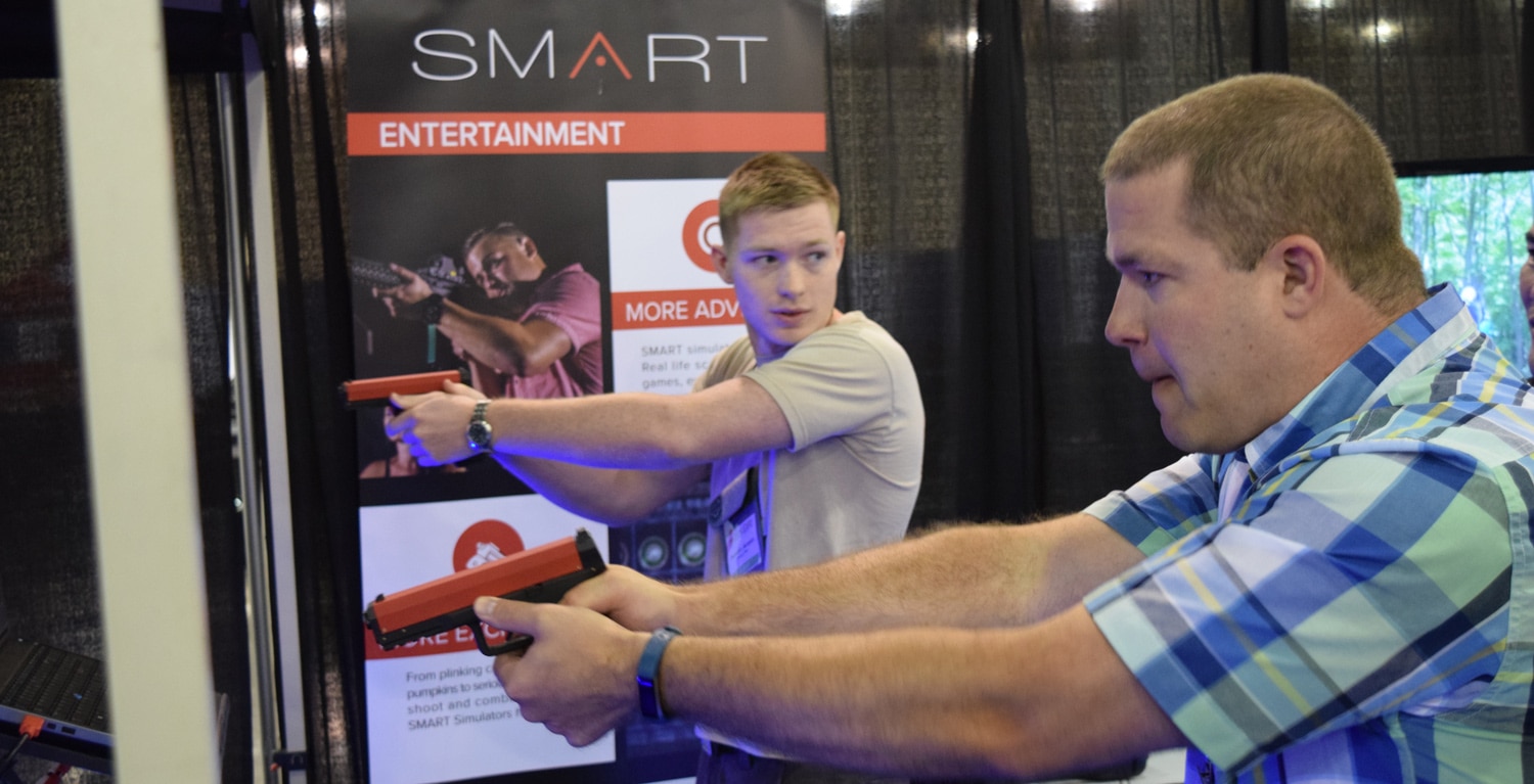 Two men who are quite possibly relatives shoot at one of the many simulators on the show floor. (Photo: Daniel Terrill/Guns.com)