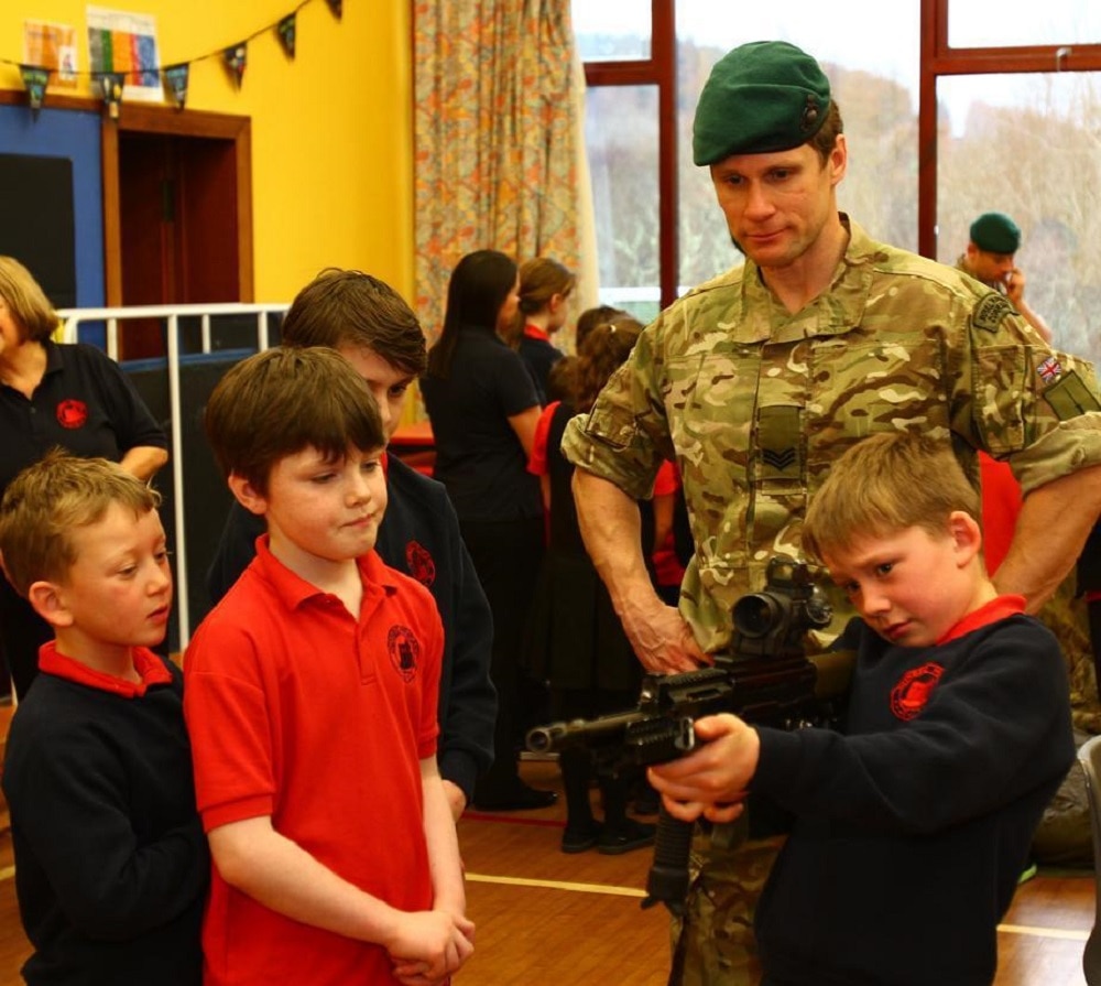 A Royal Marine shows his firearm to students during a previous visit. (Photo: The Scottish Sun/Kevin McGlynn)