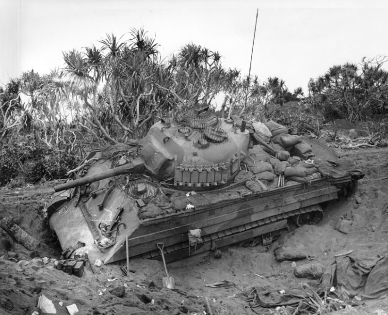 Photo caption: "Iwo Jima, February 21, 1945. Burrowed in the Sand: A Marine medium tank that couldn't navigate the soft volcanic sand on Iwo, is track deep in a pit off the beach. This loose sand of the island proved an asset to the Japanese defenders."