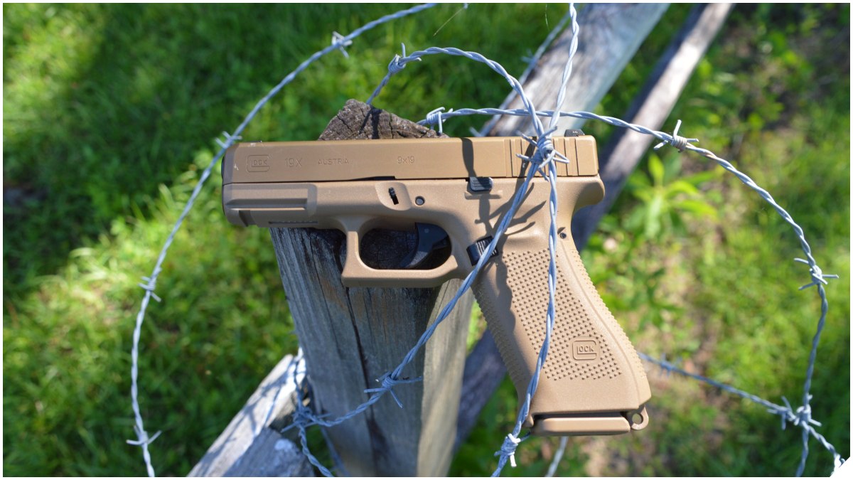 Glock G19X on a wooden fence encased in barbed wire