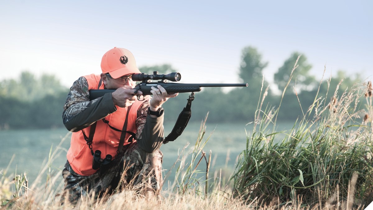 A man in hunter's orange aims a Ruger rifle