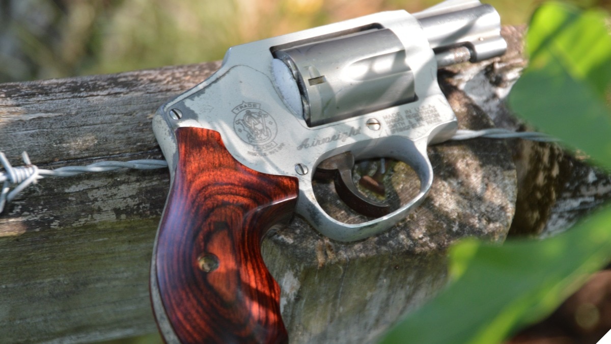  A S&W 642 J-frame snub nosed revolver on a fence with barbed wire 