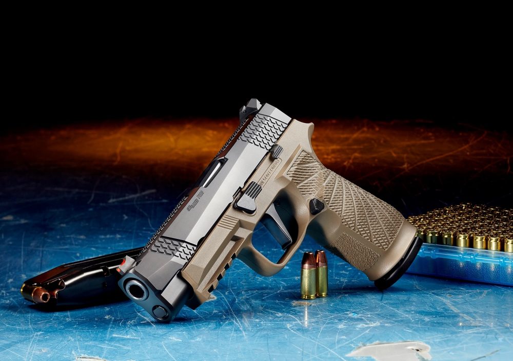 A tan Wilson Combat WCP320 pistol with a SIG-branded magazine on a wooden table with a Wilson Combat logo in the background