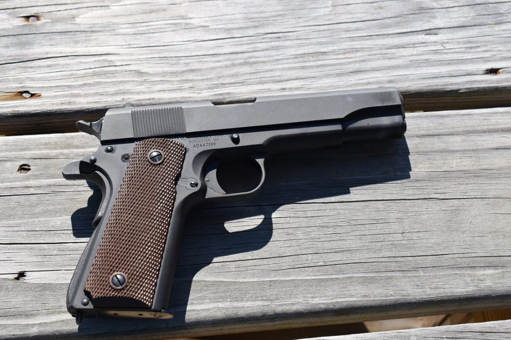 An Auto-Ordnance M1911 on a wooden tabletop in bright sunlight